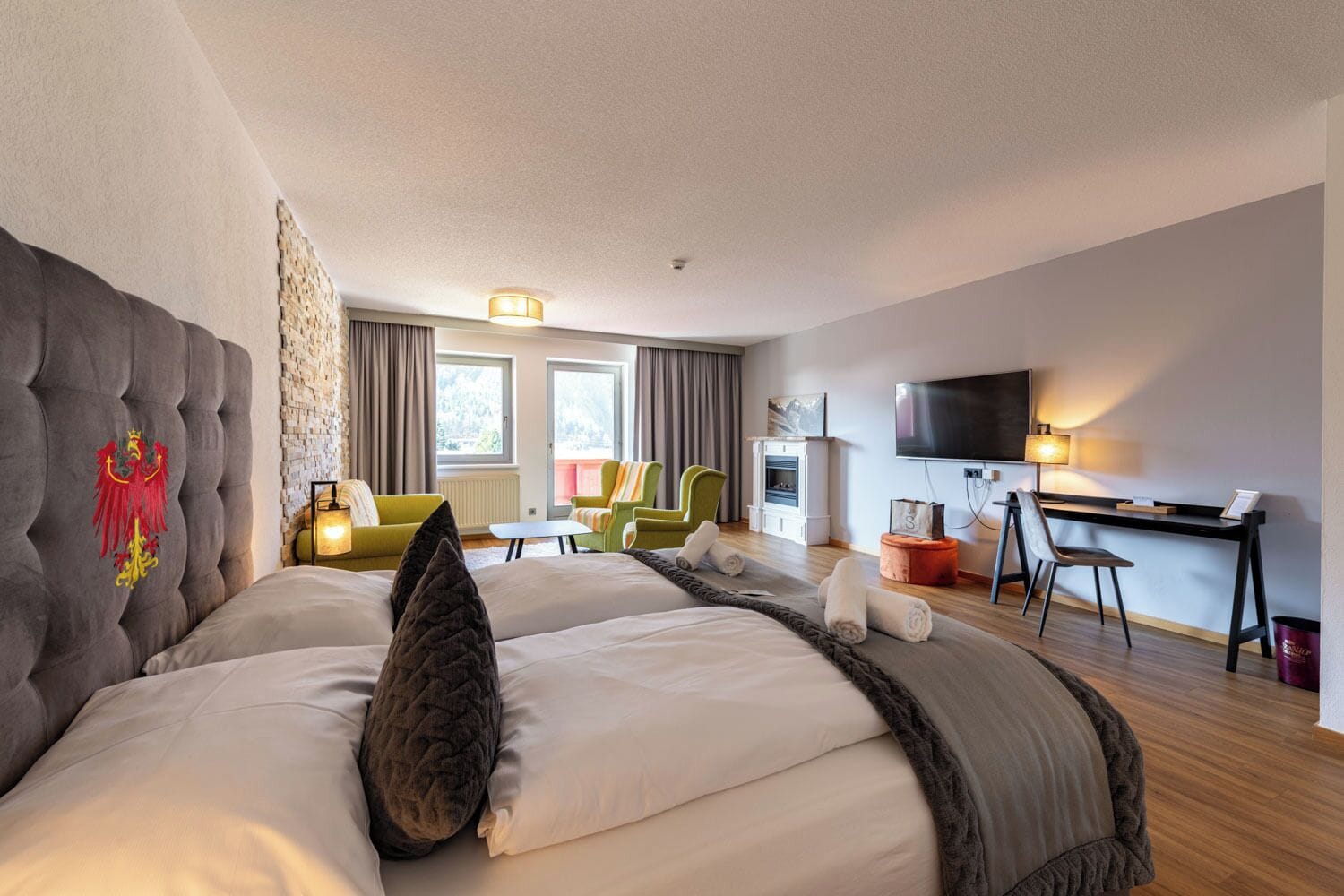 Une chambre d’hôtel avec un grand lit, un bureau, une télévision et une cheminée.