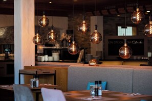 Interior de restaurante con lámparas esféricas colgantes, asientos acolchados y una barra de fondo.