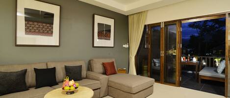 A modern living room with a sectional sofa, a round coffee table, and a glass door leading to an outdoor area.