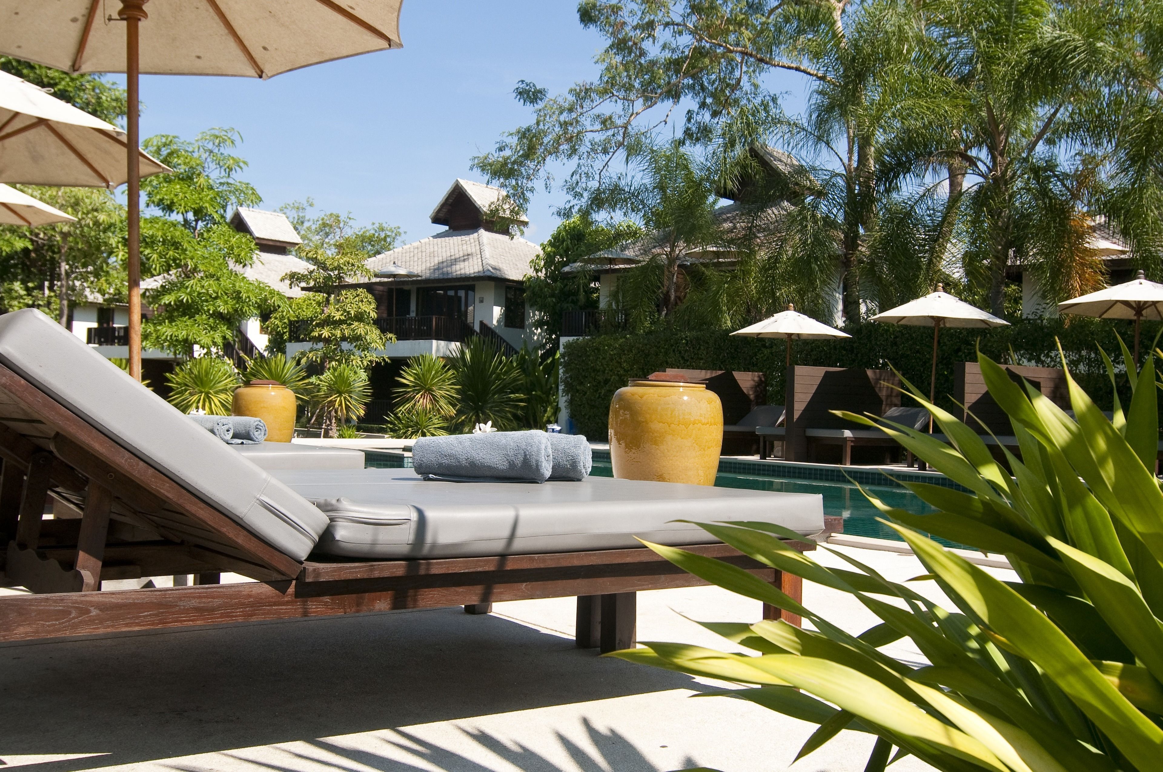 A poolside area with lounge chairs, umbrellas, and a large decorative vase.