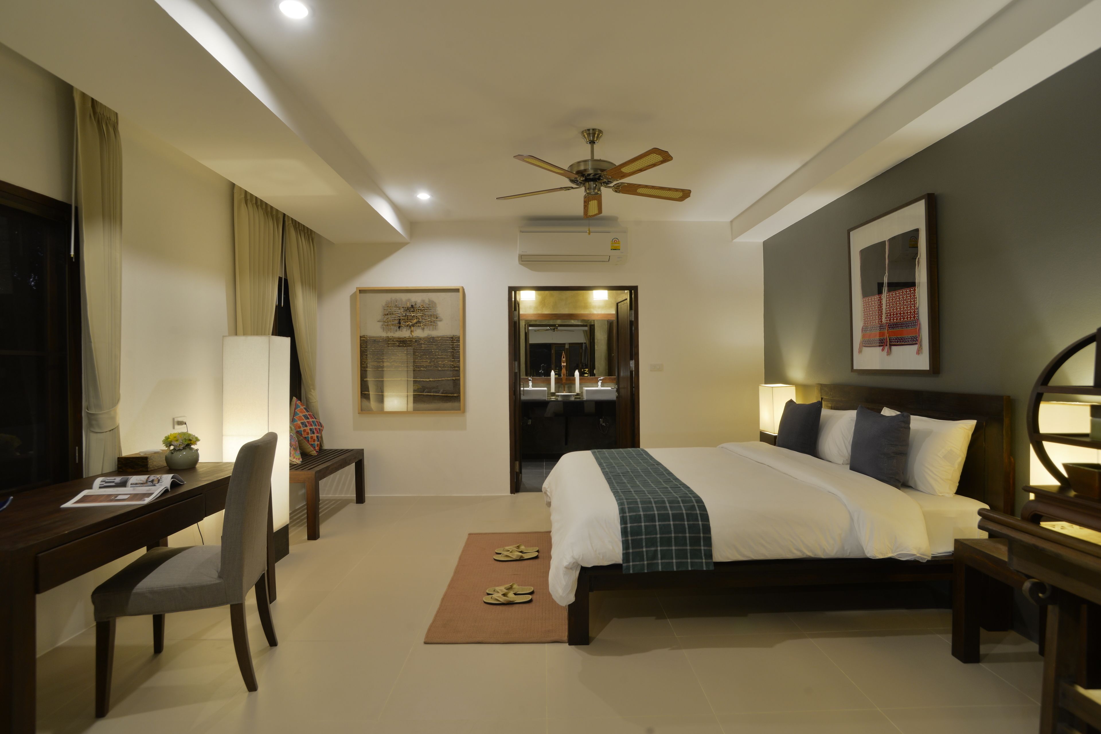 A hotel room with a bed, desk, chair, and a ceiling fan.