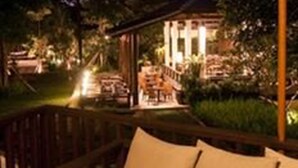 Uma área de estar aconchegante ao ar livre, com uma mesa, um livro e uma bebida.