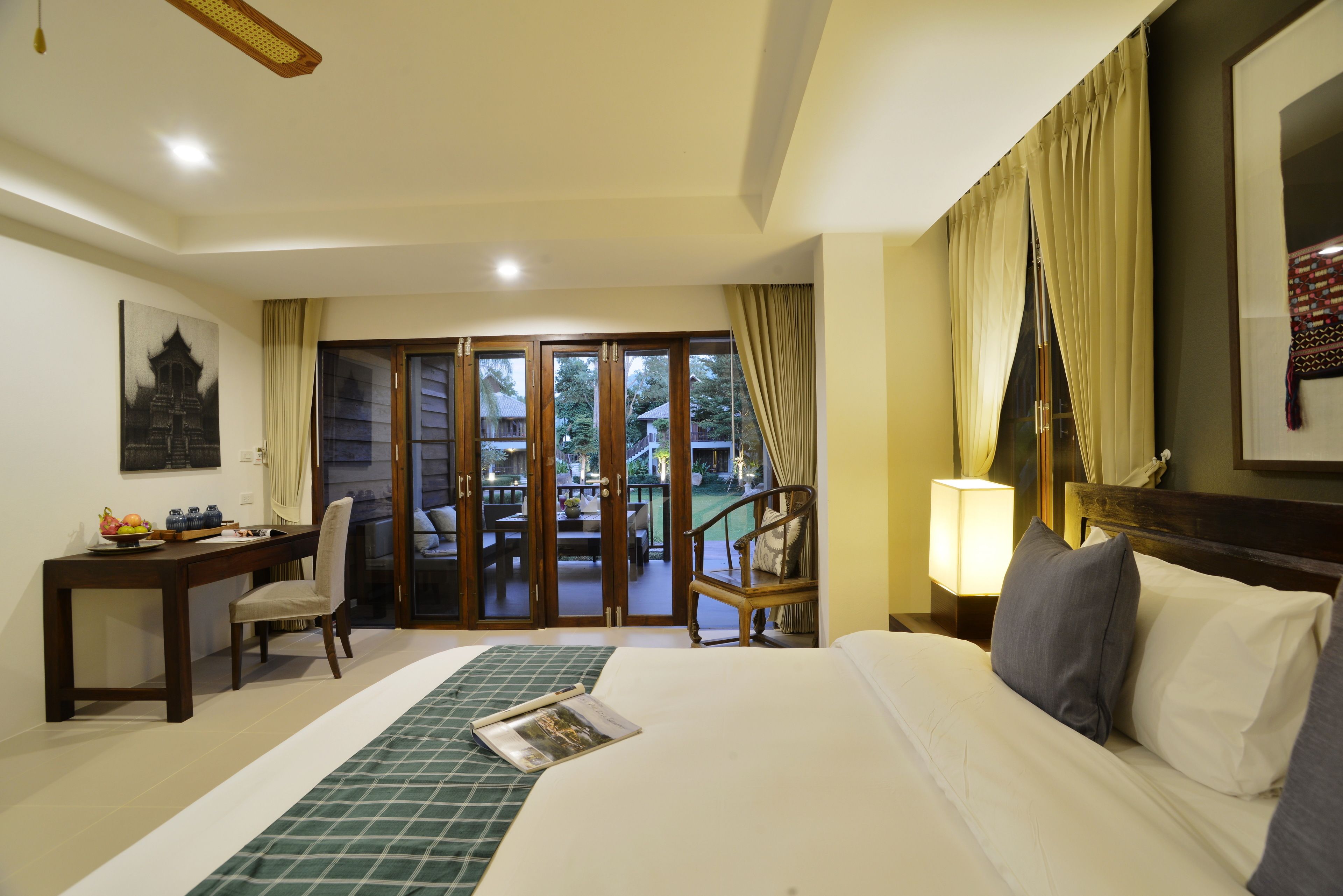 Habitación de hotel con cama, escritorio, silla, mesa y vista al exterior.
