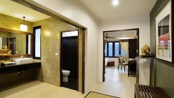 A modern bathroom with a sink, toilet, and shower. There is a wooden bench and a chair in the room.