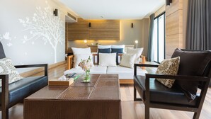 A modern living room with a sofa set, a coffee table, and a decorative wall mural. - The Greenery Resort Khao Yai (Pak Chong)