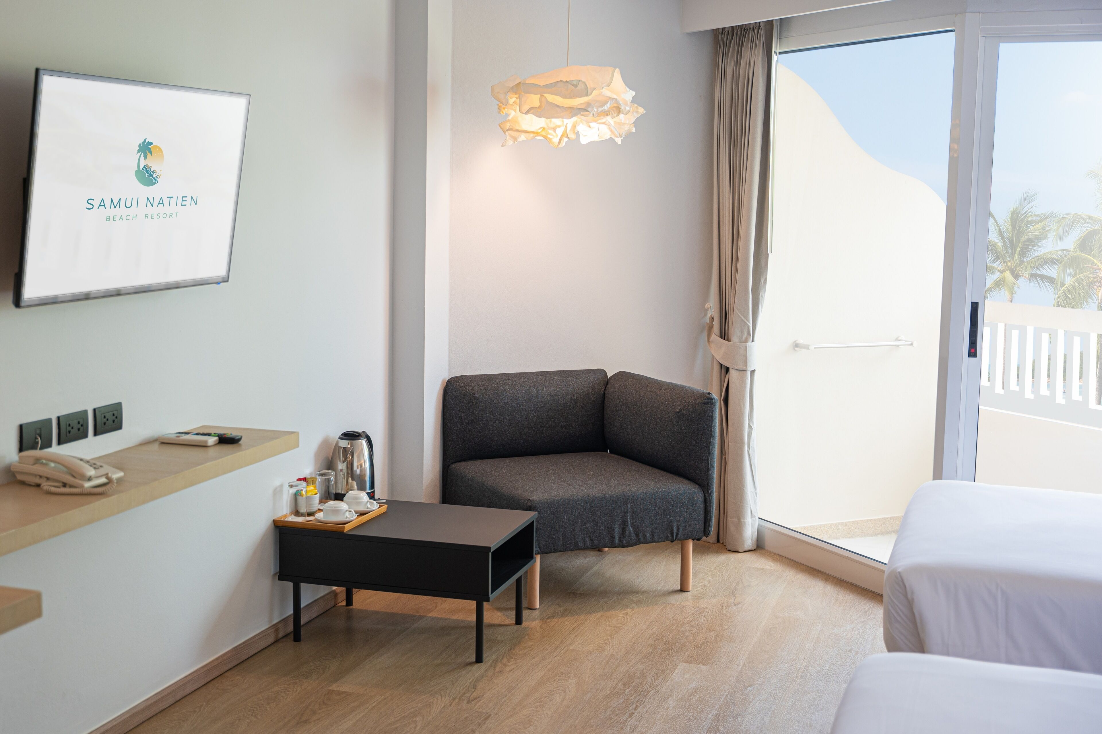 Une chambre d’hôtel équipée d’un lit, d’un bureau avec un téléphone, d’une machine à café et d’un plateau avec des tasses et une télécommande.