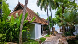 Un complexe hôtelier tropical doté d’un toit en tuiles, d’un chemin en pierre et d’une végétation luxuriante.