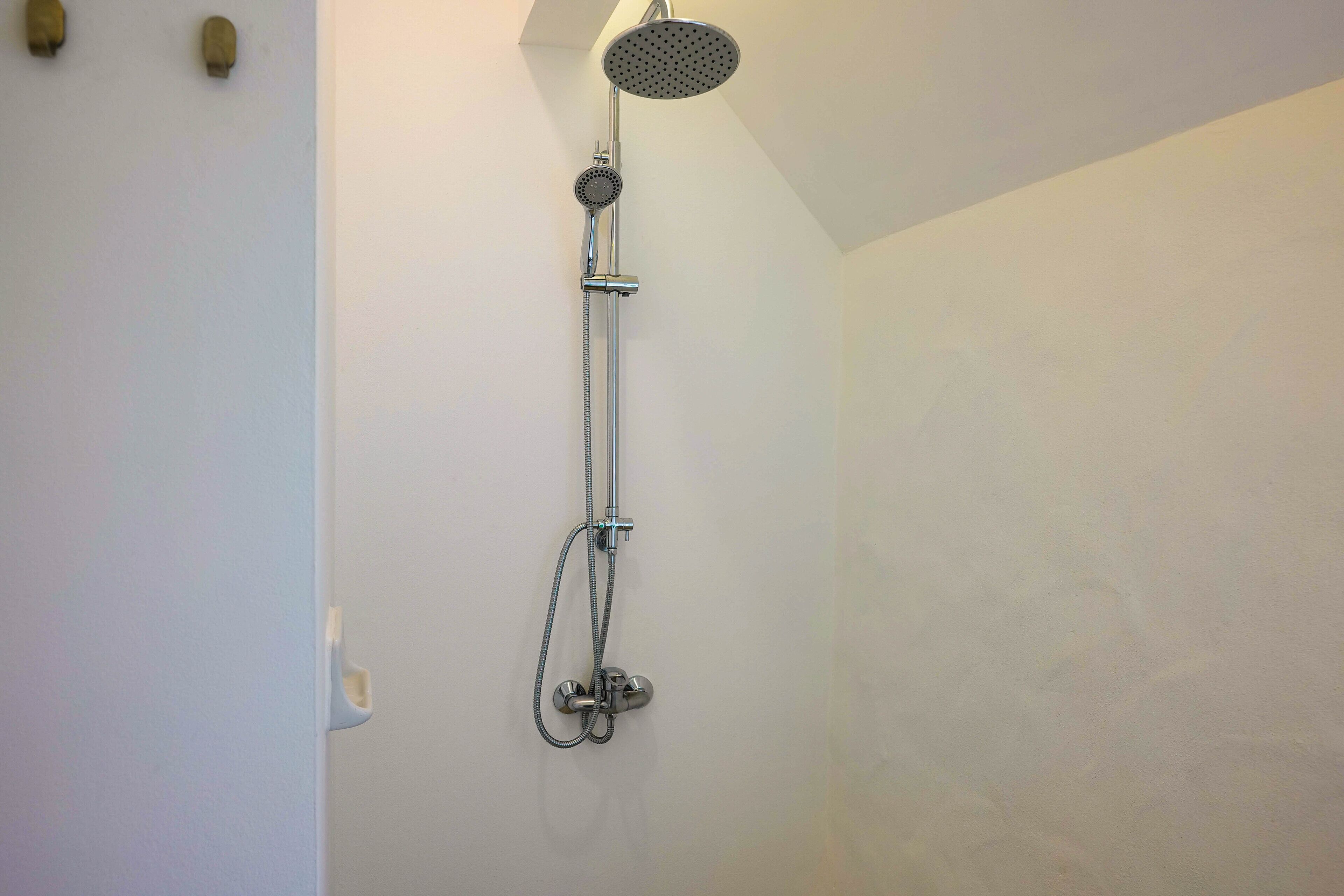 Une douche équipée d’un pommeau de douche à main et de commandes murales.