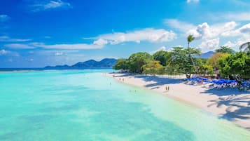 Am Strand, weißer Sandstrand, Liegestühle, Sonnenschirme