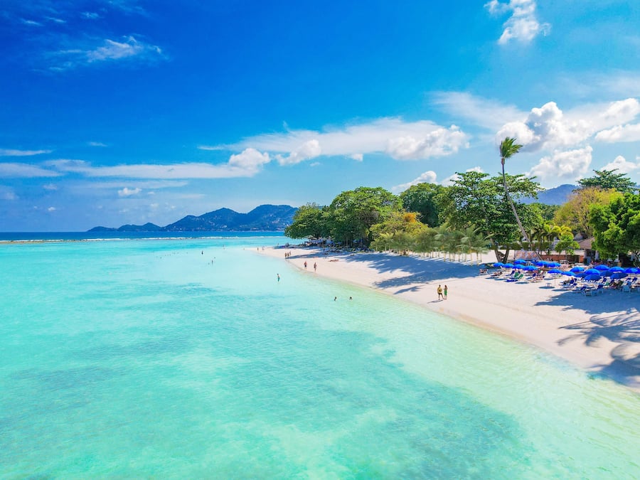 En la playa, arena blanca, sillas reclinables de playa, sombrillas