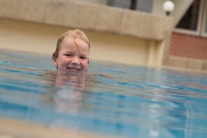 A child in a swimming pool with a blurred background.