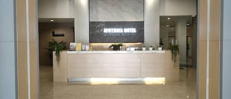 A reception desk with a marble top, a sign reading 'AYOTHAYA HOTEL AYUTHAYA THAILAND,' and a plant on the left.