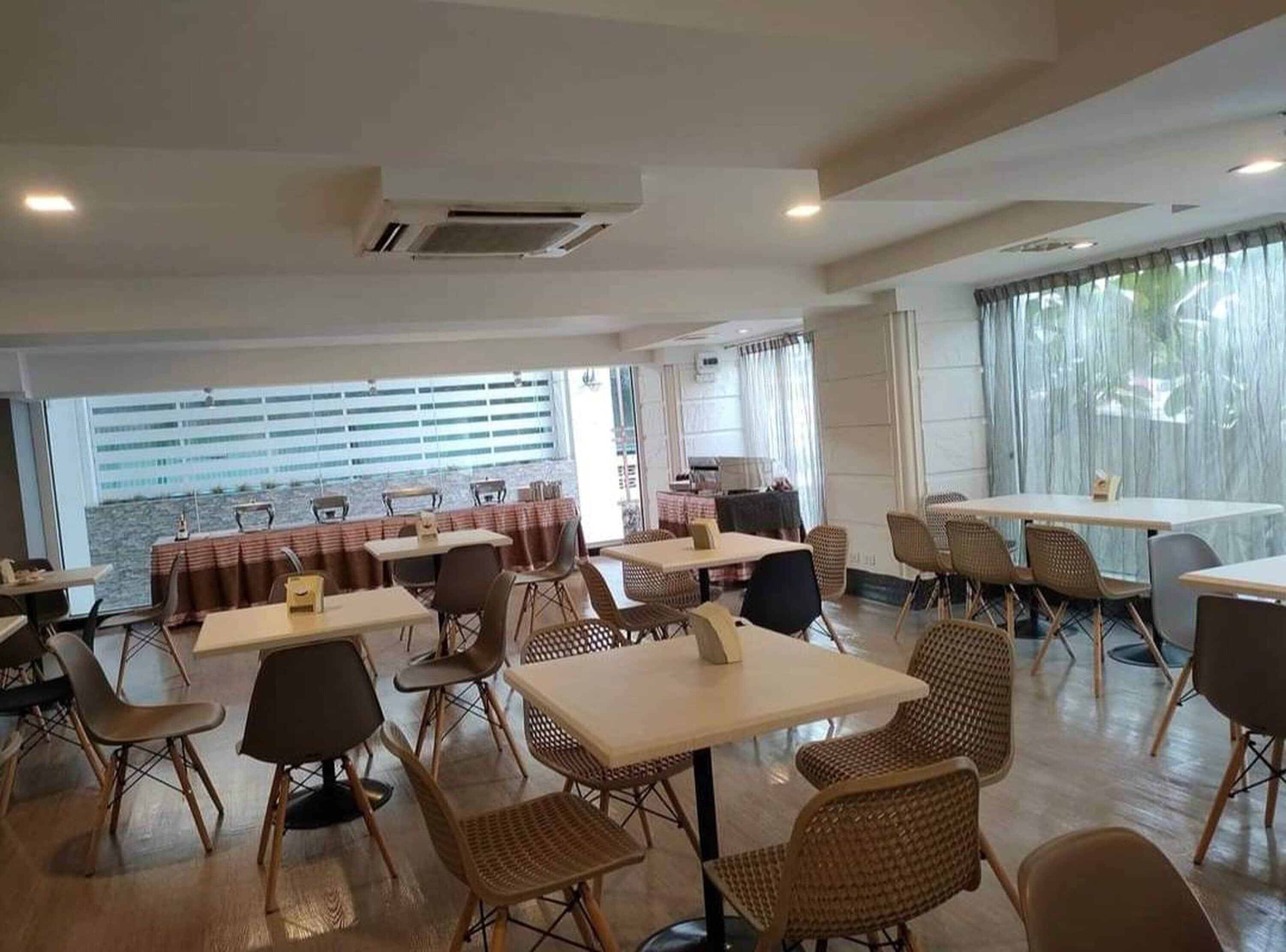 A restaurant with tables and chairs, large windows, and a view of the outdoors.