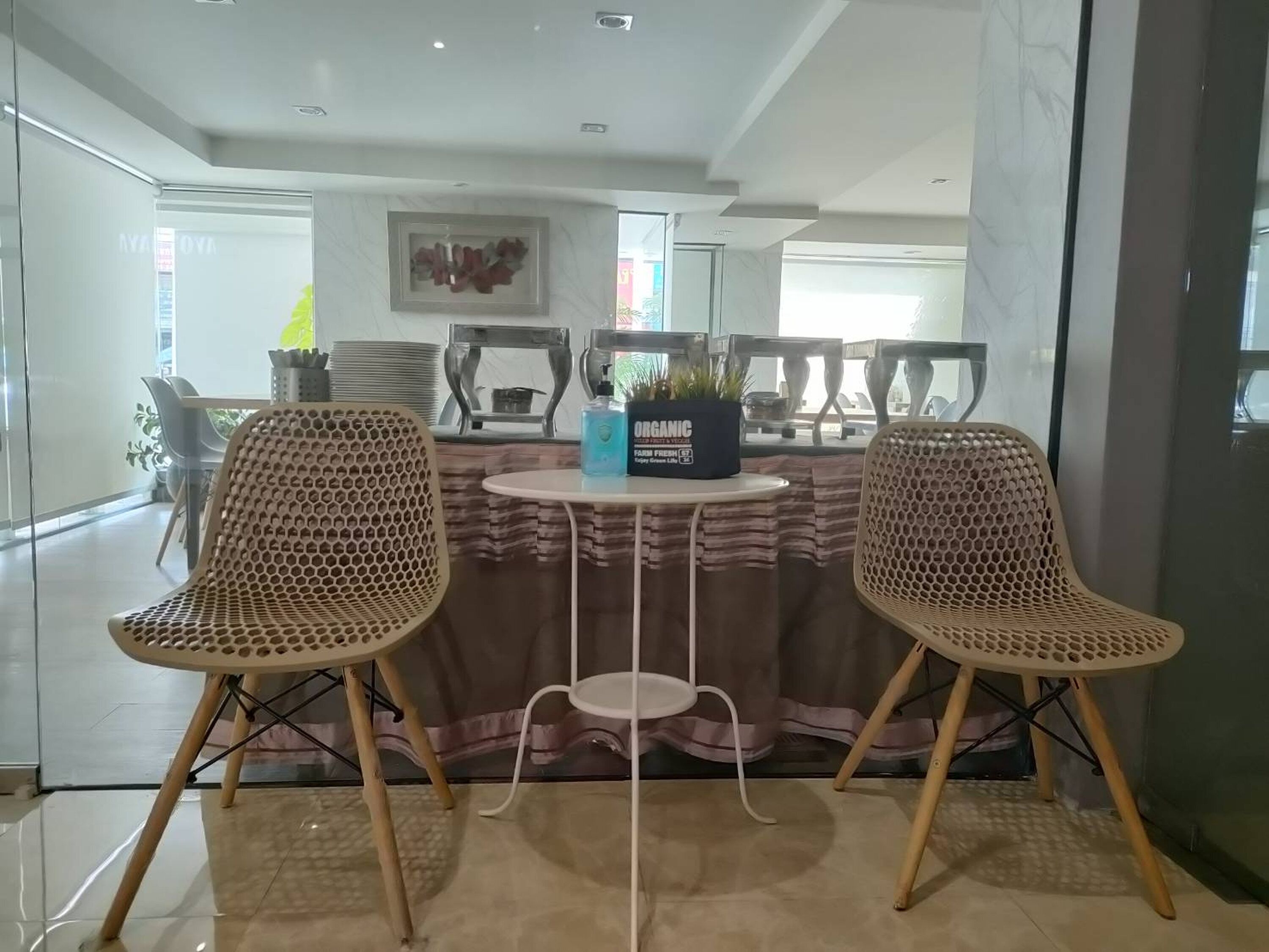 A dining area with two wicker chairs, a round table, and a potted plant.
