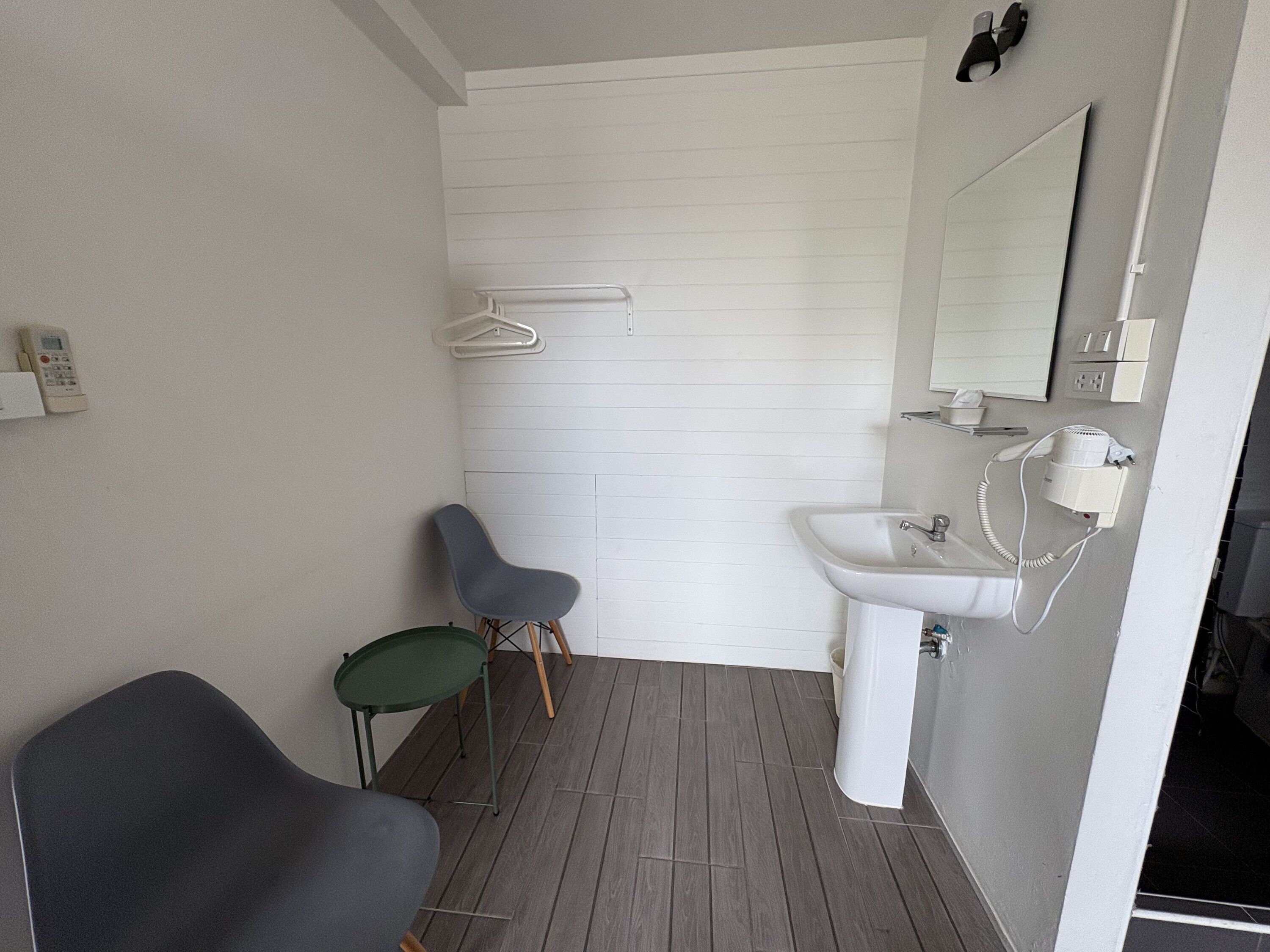A bathroom with a sink, mirror, towel rack, and two chairs.