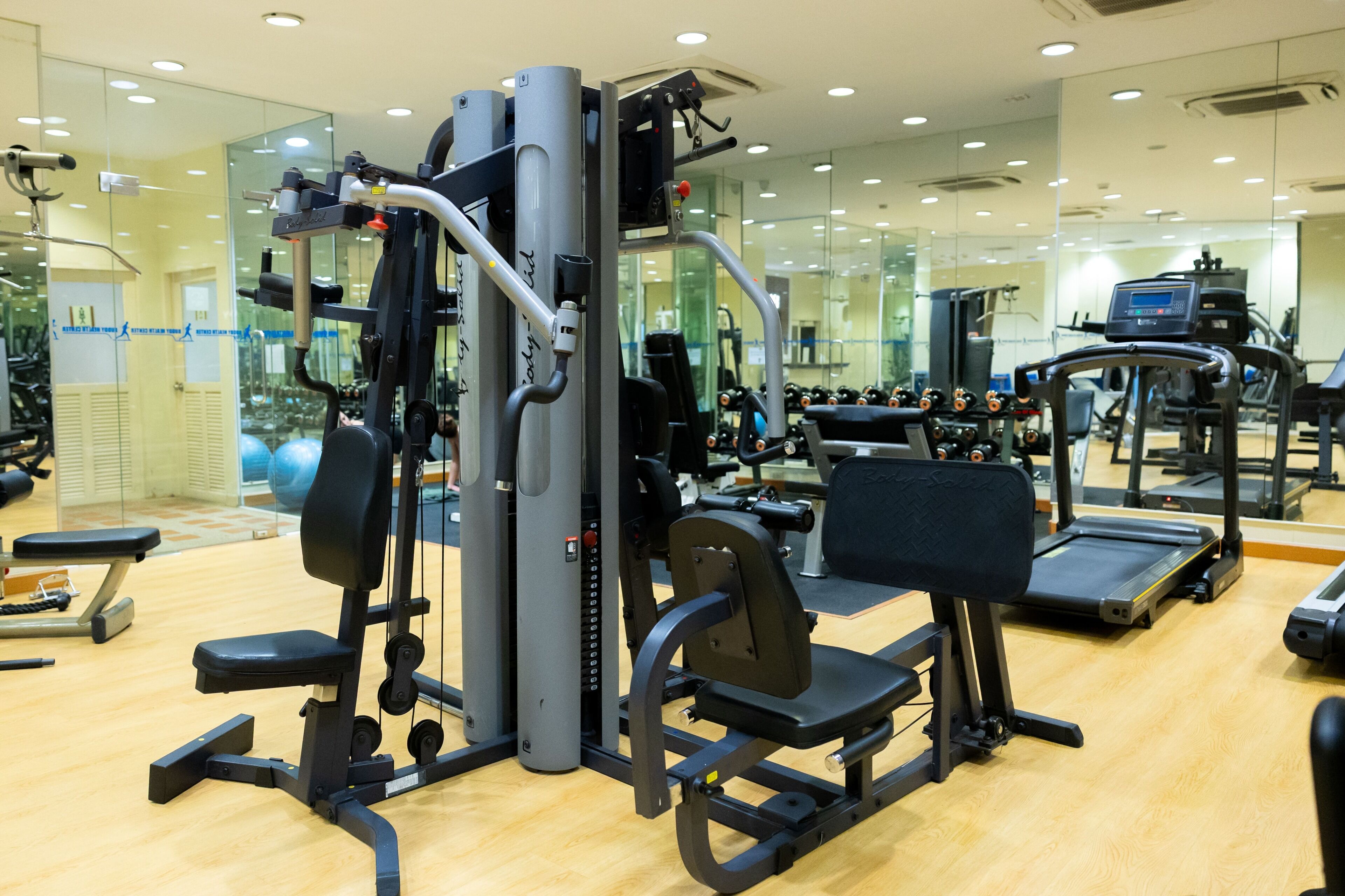 A gym with exercise equipment, a treadmill, and a mirrored wall.