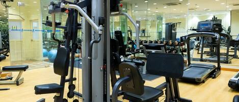 A gym with exercise equipment, a treadmill, and a mirrored wall.