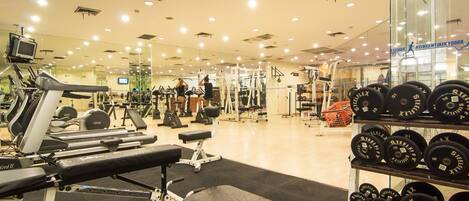 A gym with various exercise equipment, including treadmills, weight machines, and free weights.