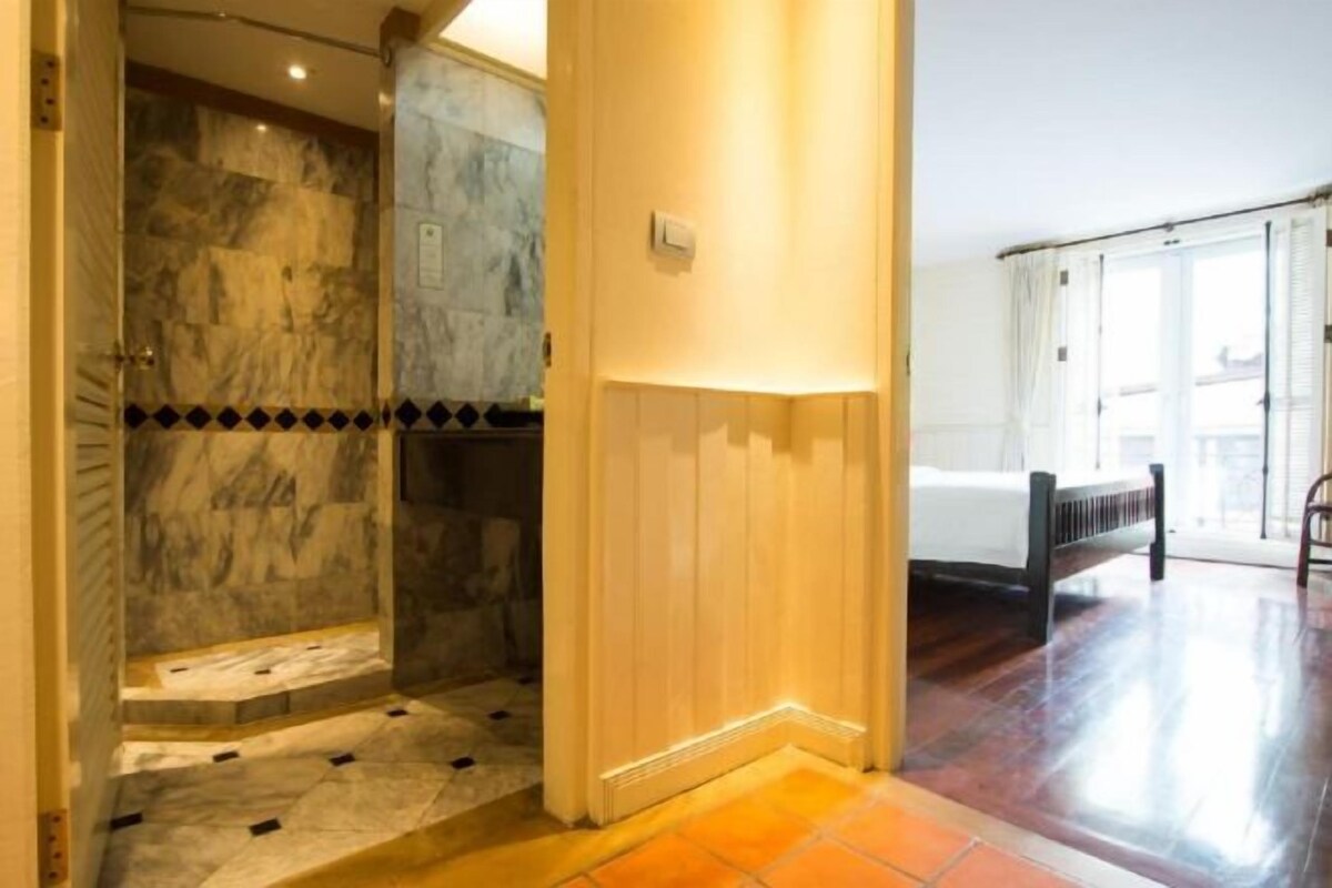 Habitación de hotel con ducha de mármol, una cama y vistas al exterior.