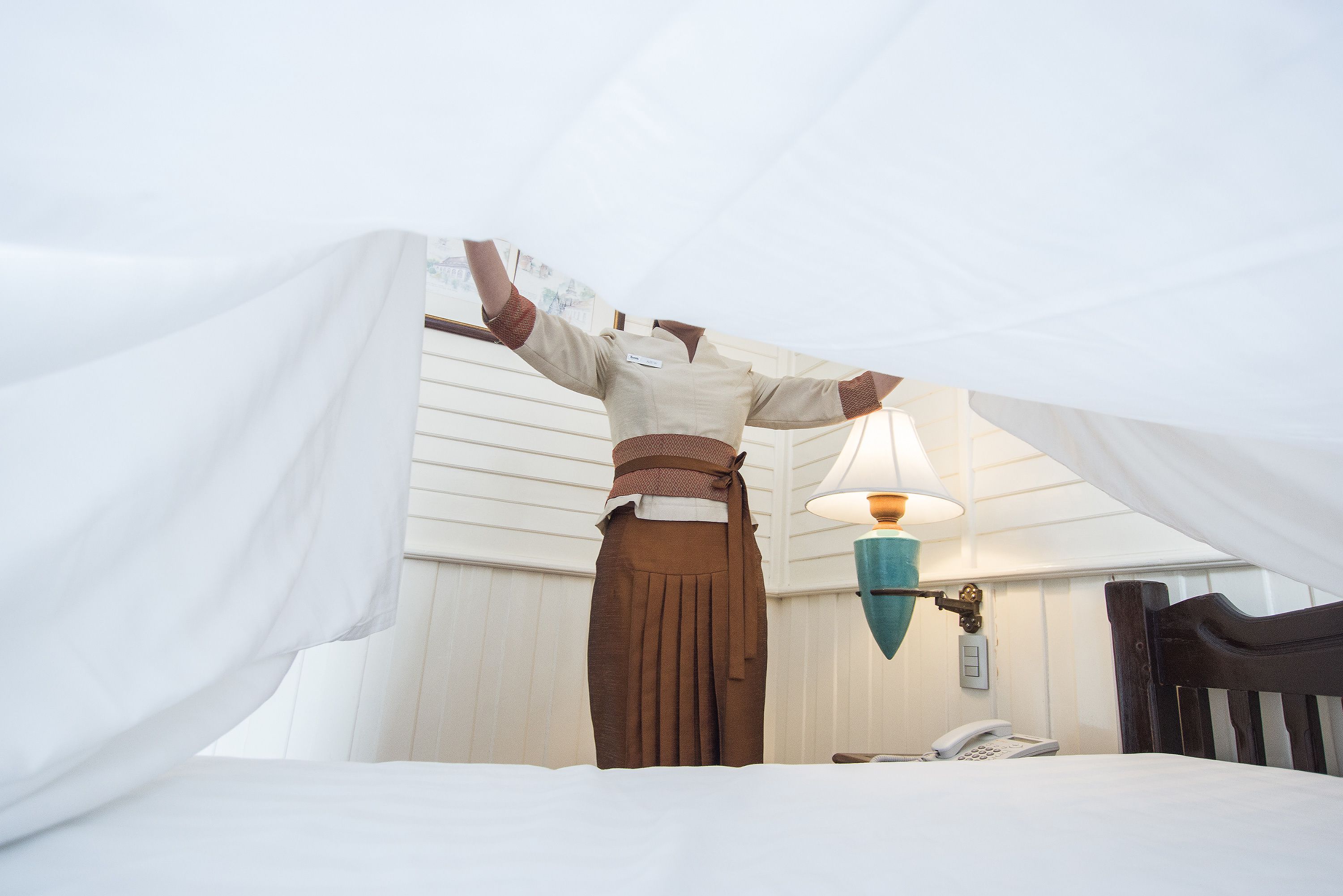 Quarto com cama, luminária e telefone na mesinha de cabeceira.