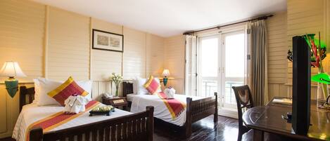A hotel room with two wooden beds, a desk, and a chair.