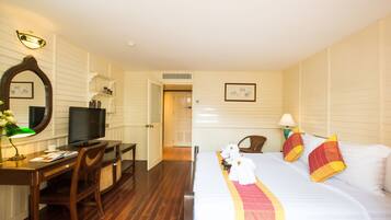 Quarto de hotel com uma cama, uma escrivaninha com computador, televisão e espelho.