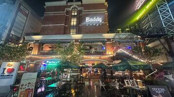 A building with a prominent 'Buddy Lodge' sign, outdoor seating with umbrellas, and a visible McDonald's sign.