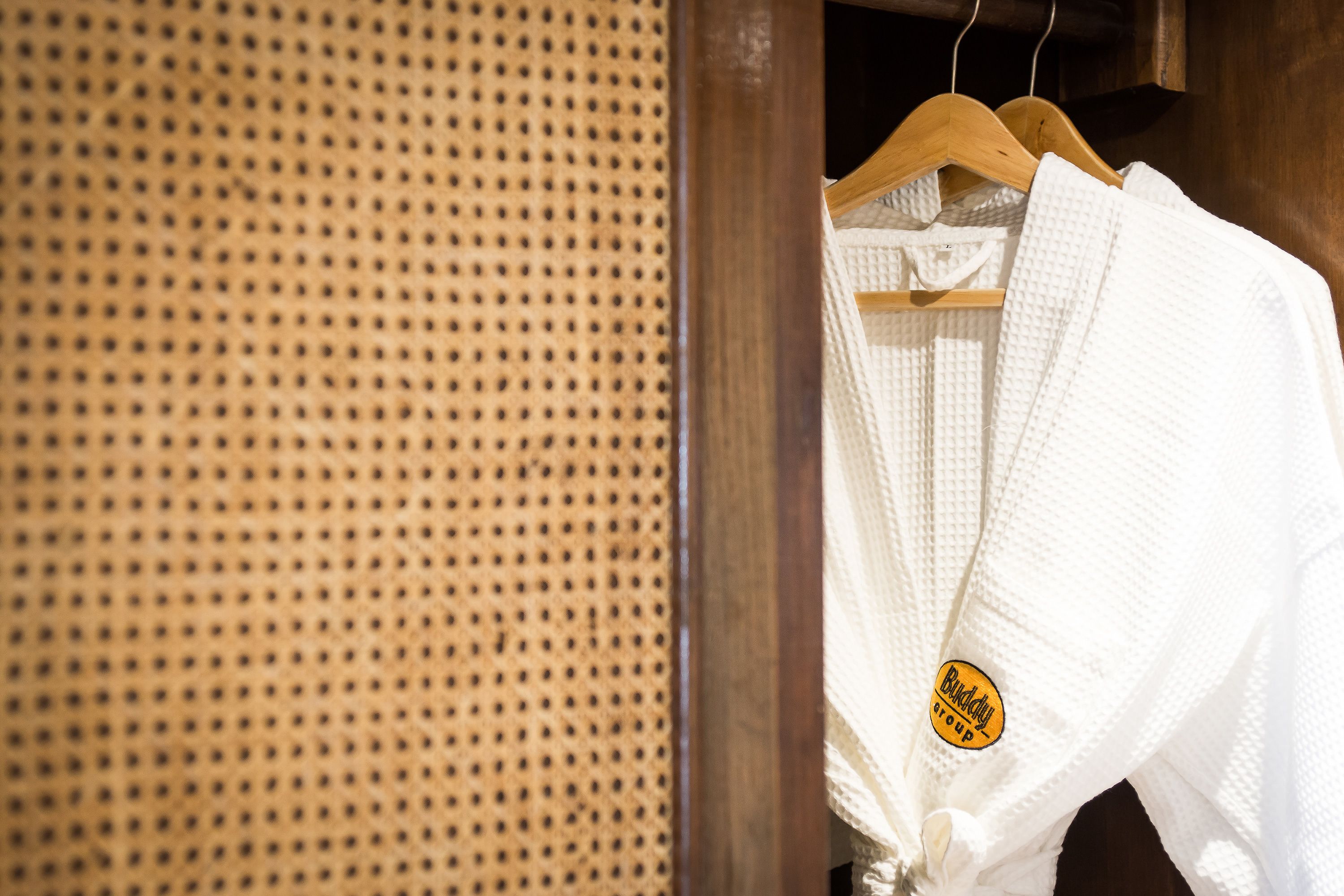 A wooden hanger with a white robe hanging on it.
