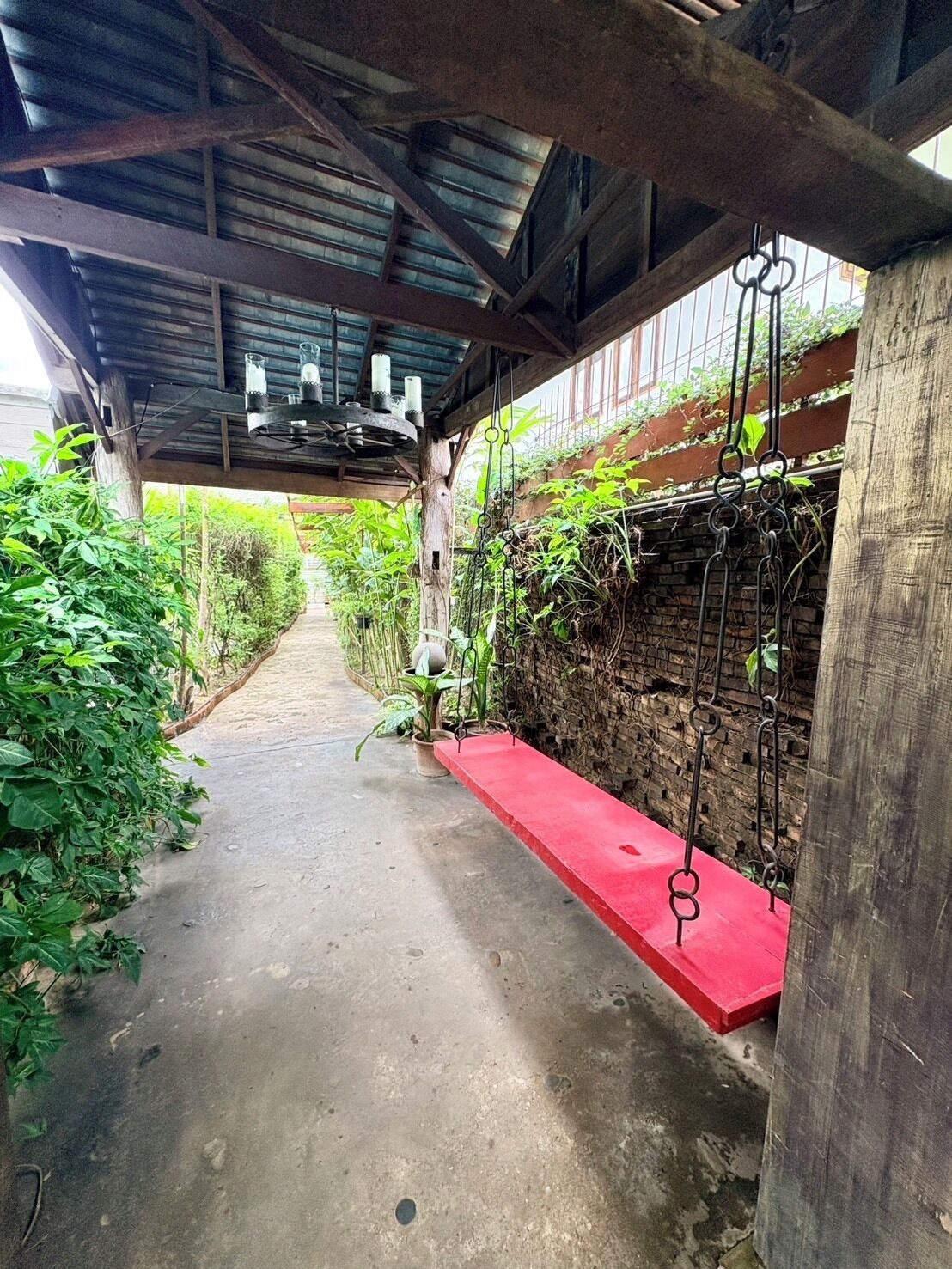 Un sendero cubierto con un banco rojo, barandillas de metal y follaje a ambos lados.