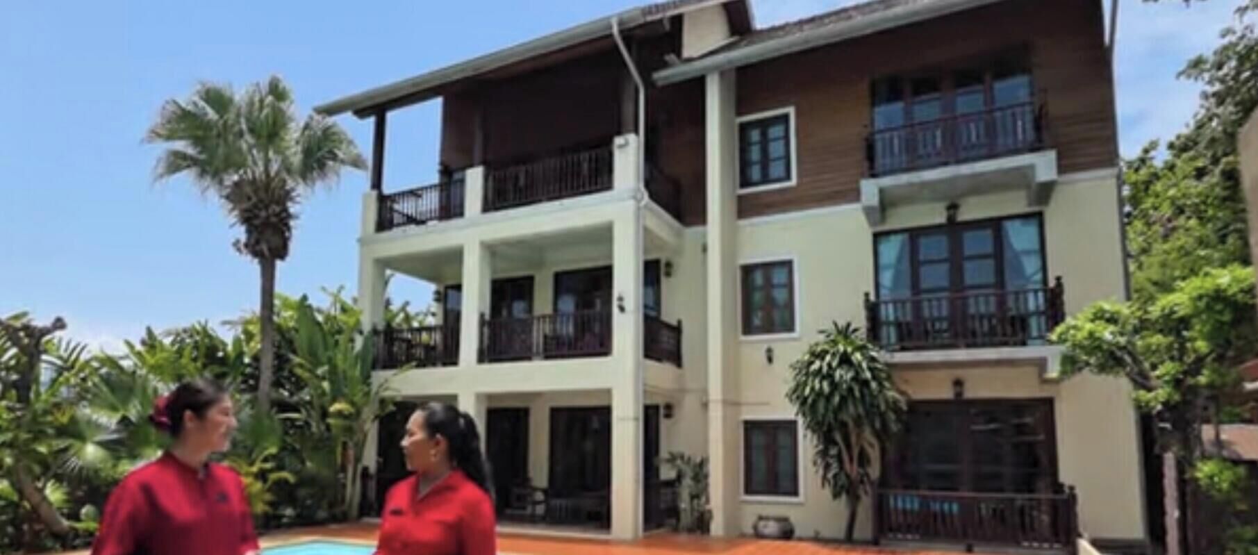 A multi-story building with balconies, large windows, and a pool area.
