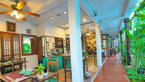 A traditional restaurant with wooden furniture, a tiled floor, and a green plant wall. - Shewe Wana Suite Resort (Chiang Mai)