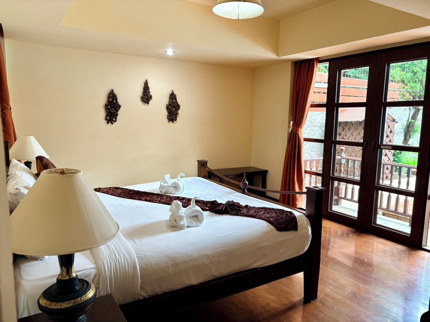 A hotel room with a bed, a lamp, a desk, and a view of the outdoors.