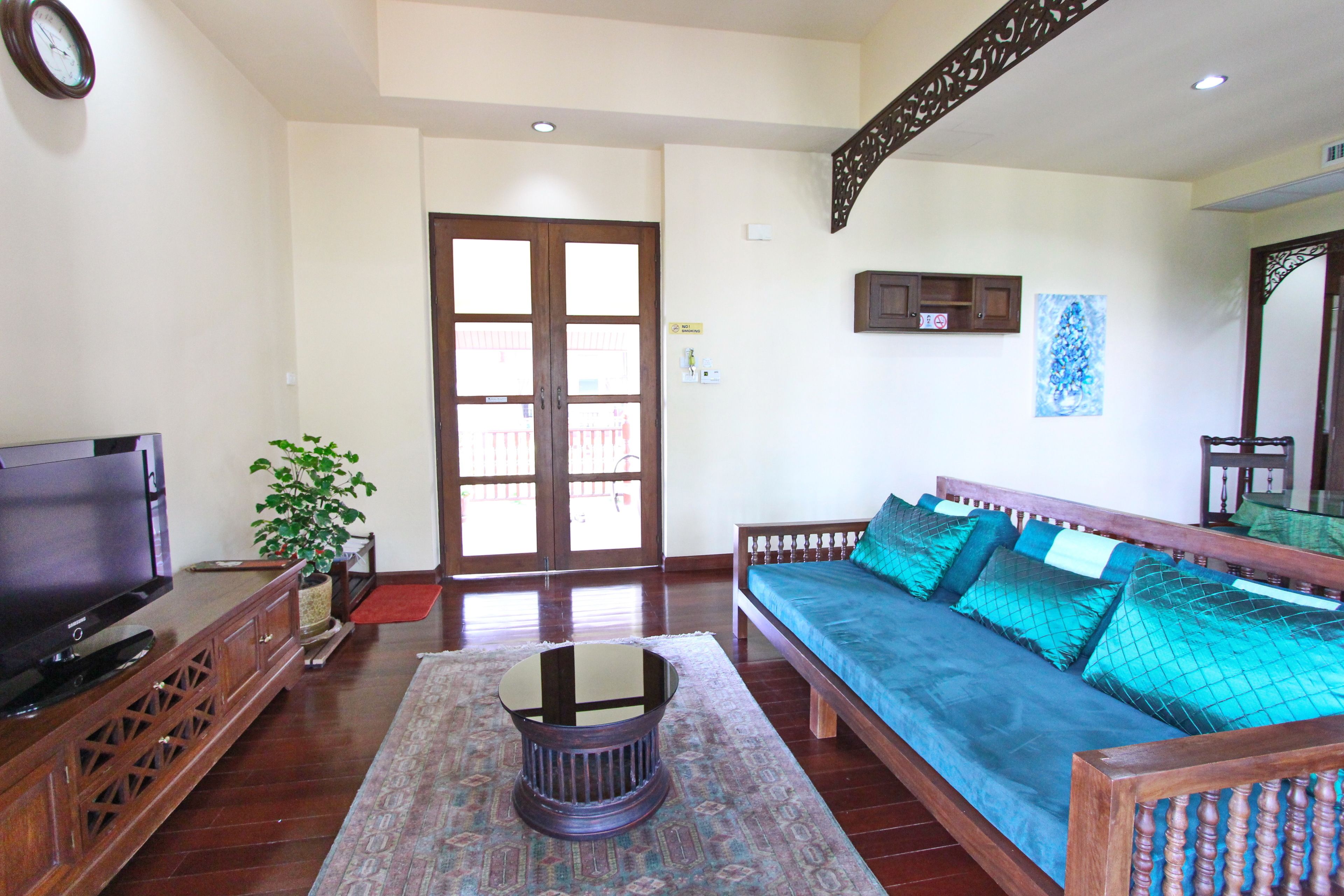 A living room with a sofa, TV, wooden cabinet, and a potted plant.