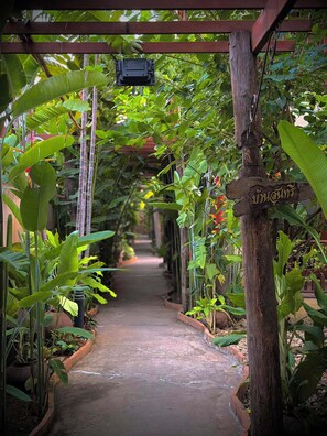 A narrow pathway flanked by lush greenery and a wooden signpost. - Shewe Wana Suite Resort (Chiang Mai)