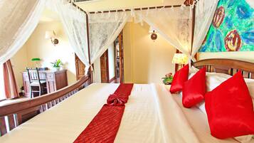 A 1 bedroom suite with a bed, red pillows, a red runner, and a canopy.