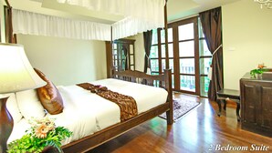 A 2-bedroom suite with a large bed, a nightstand, a lamp, and a view of the outdoors through a window. - Shewe Wana Suite Resort (Chiang Mai)