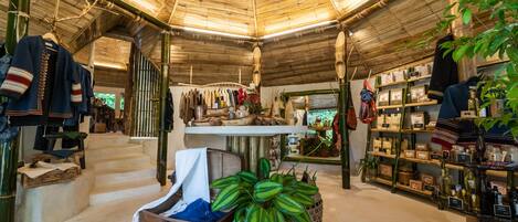 A boutique hotel interior with a bamboo ceiling, wooden furniture, and various items for sale.