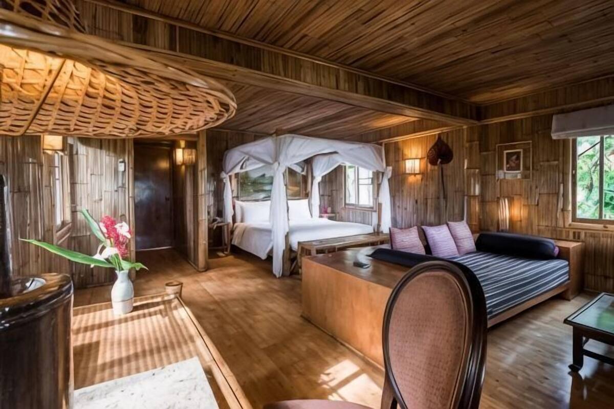 A wooden interior with a bed, a sofa, a table, and a chair.