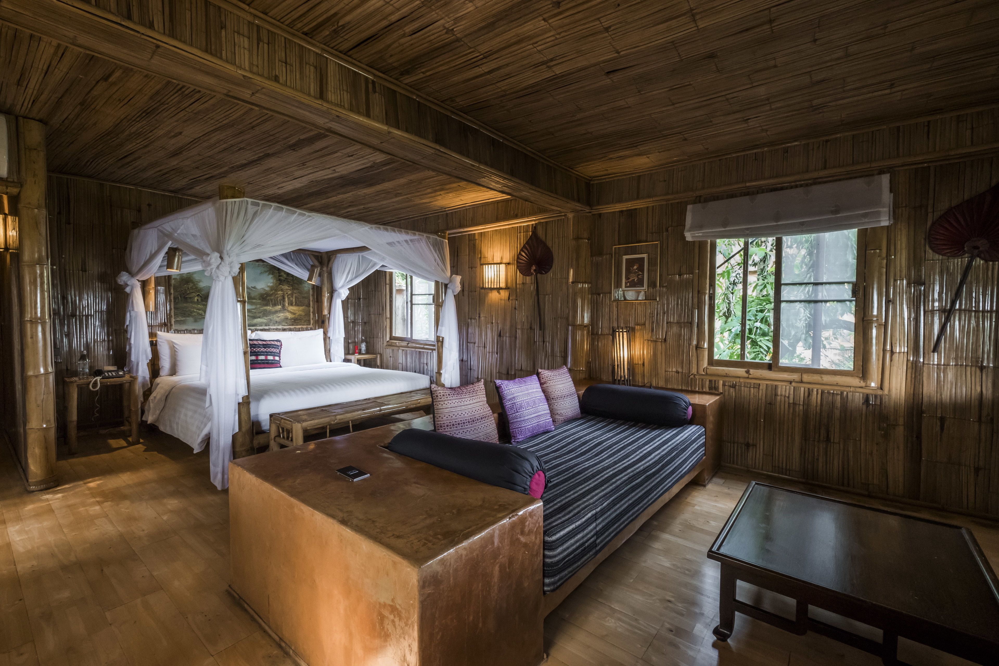Een kamer met een bed, een slaapbank, een tafel en een hemelbed.