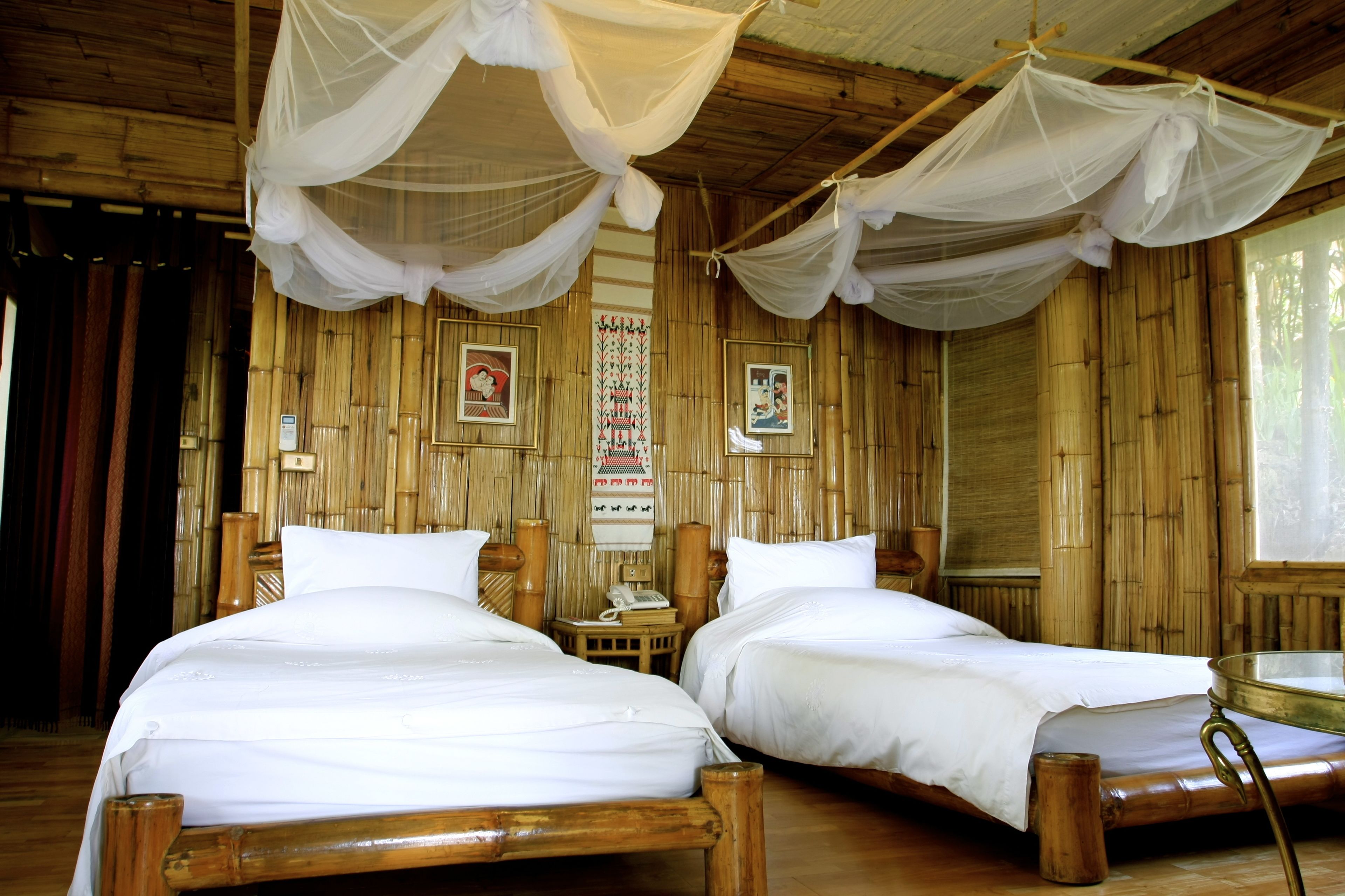 A room with two wooden beds, white bedding, and a mosquito net.
