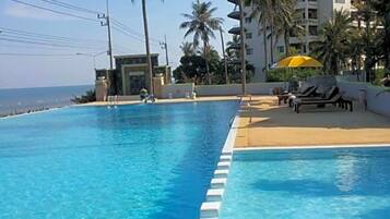 Una piscina al aire libre, sombrillas, sillones reclinables de piscina