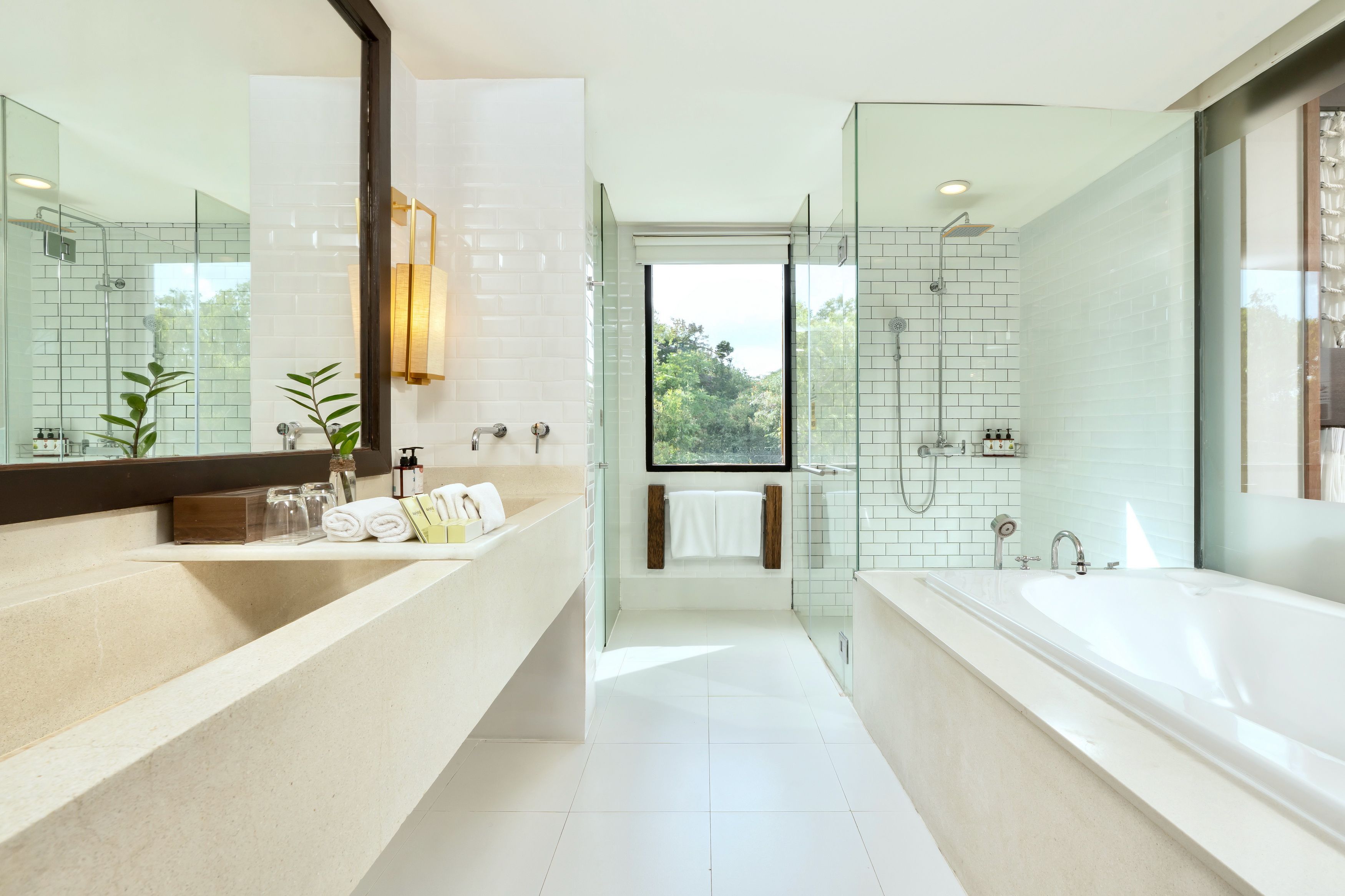 A modern bathroom with a glass shower enclosure, a large bathtub, and a vanity with a mirror.