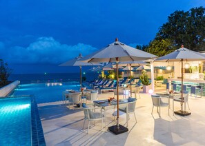 A poolside area with lounge chairs and umbrellas, a bar, and a view of the ocean. - The Rock Hua Hin Beachfront Spa Resort (Hua Hin)