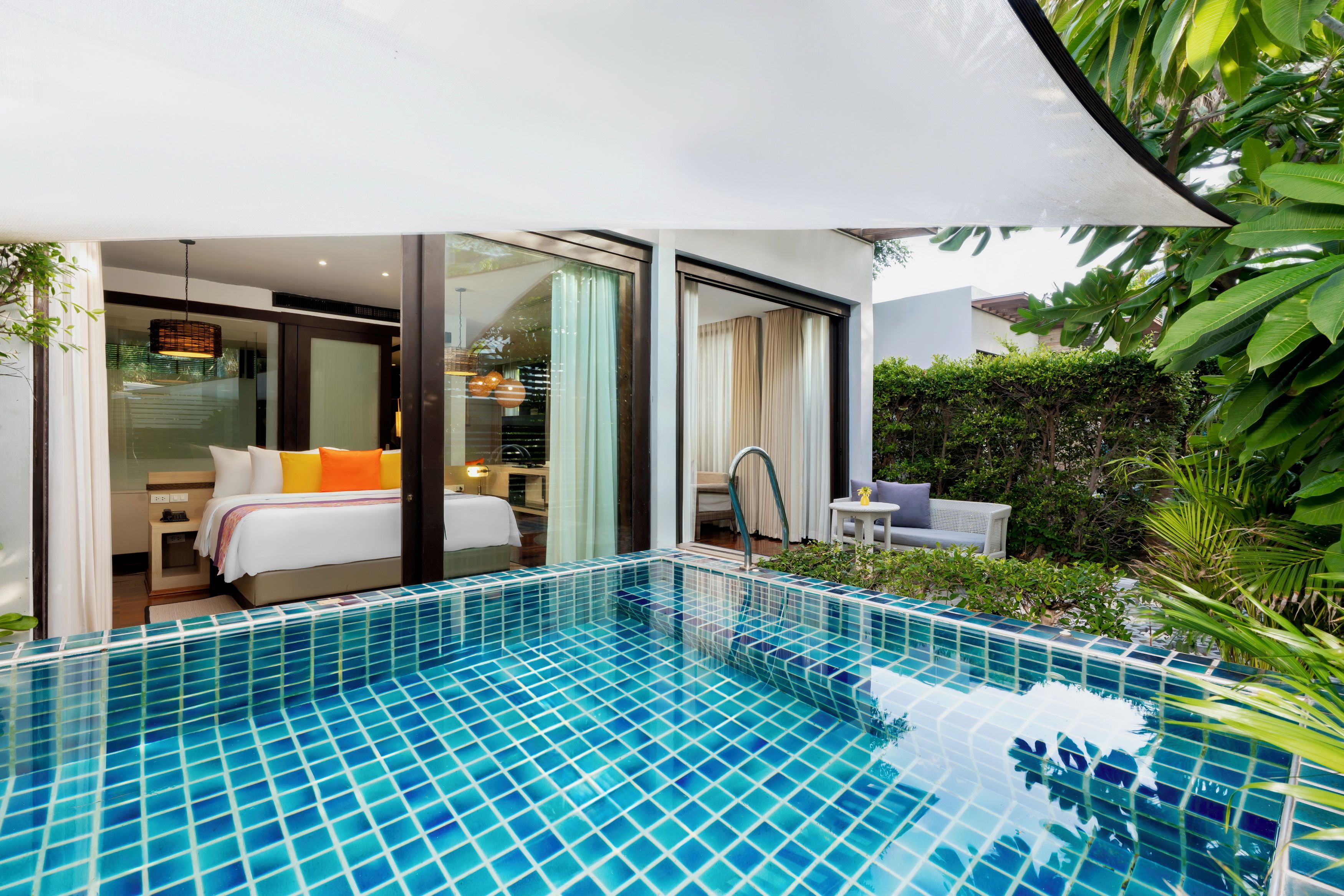 Ett modernt hotellrum med en glasdörr som leder ut till en balkong, en liten pool och en matplats.