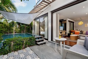 A modern outdoor pool area with a glass enclosure, surrounded by greenery and a covered seating area with a small table and chairs. - The Rock Hua Hin Beachfront Spa Resort (Hua Hin)