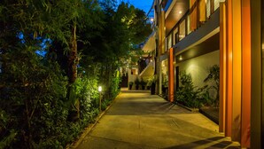 A nighttime view of a building with a covered walkway, surrounded by greenery. - The Rock Hua Hin Beachfront Spa Resort (Hua Hin)