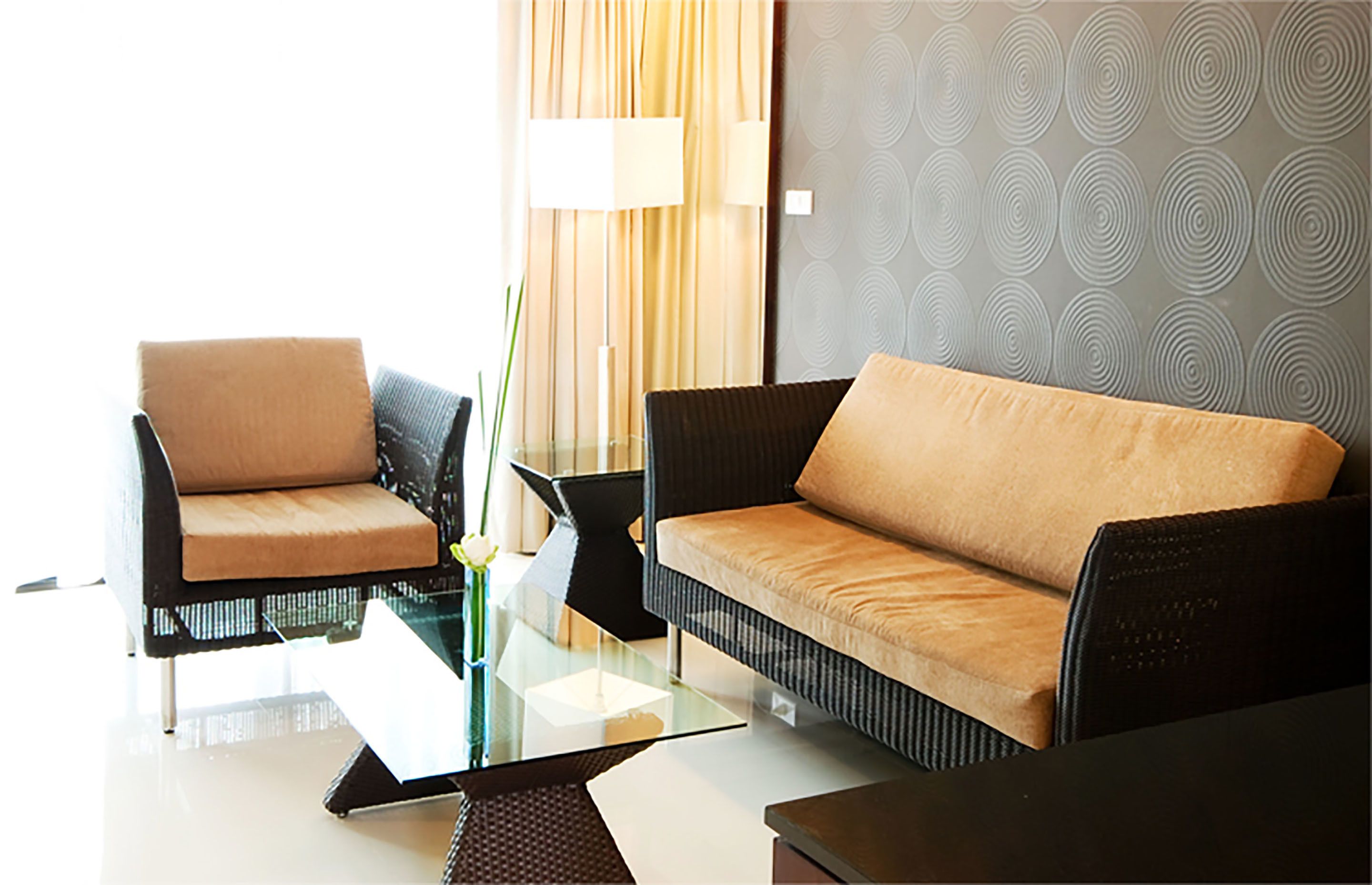 A modern living room with two sofas, a glass coffee table, and a side table with a vase.