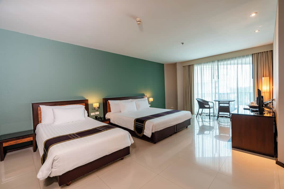 Quarto de hotel com duas camas, uma escrivaninha e uma cadeira.