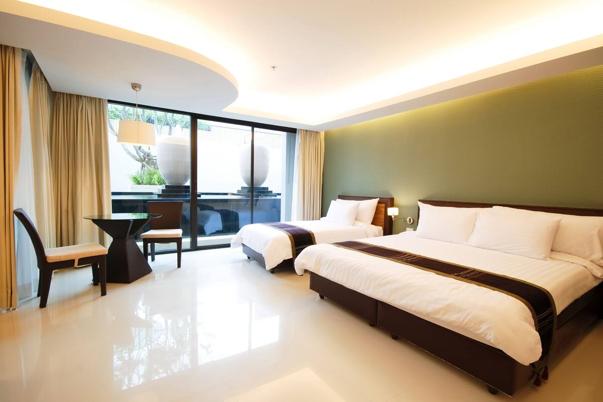 Quarto de hotel com duas camas, uma escrivaninha e uma cadeira.