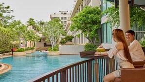 A couple sitting by a poolside with a view of a water feature and surrounding greenery. - Tara Mantra Cha Am Resort (Cha-am)